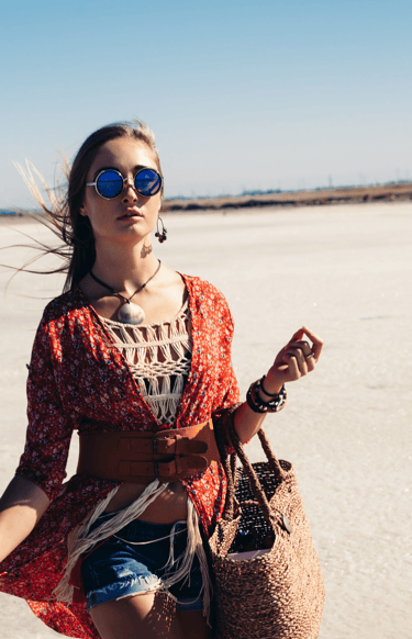 a woman in a red dress and sunglasses walking on a beach