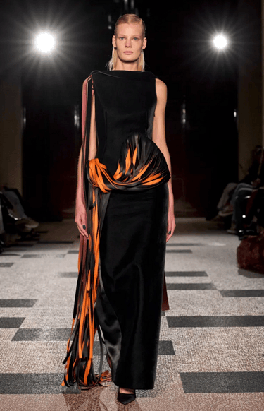 Roksanda model in black gown with orange ribbon detailing on the runway at London Fashion Week 2026.