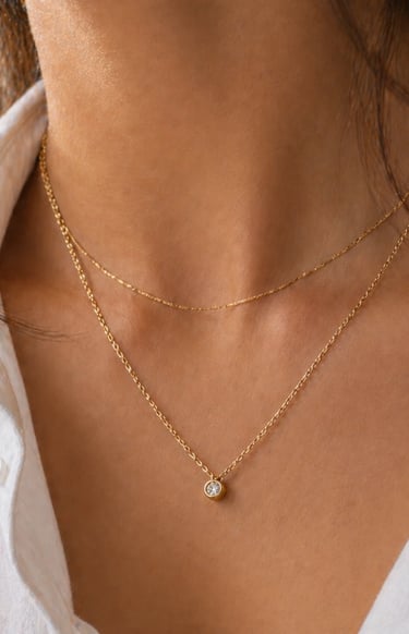 Close-up of delicate gold chain necklace with small pendant layered on simple outfit