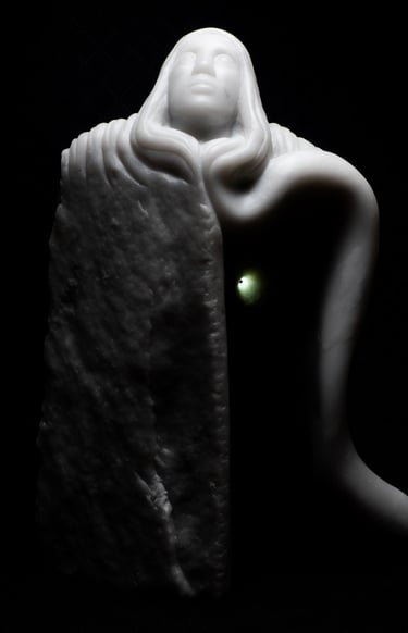 White marble sculpture of a hooded figure emerging from stone with a glowing green light.