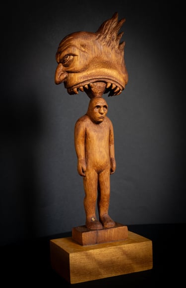 Hand-carved wood sculpture depicting a surreal creature head biting a human figure.