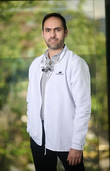 Professional male dentist in a medical coat wearing dental loupes and standing in a clinic