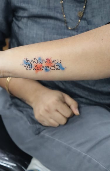 Name tattoo with orange and blue watercolor effect on hand by Dudo’s Hyderabad
