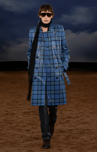 Burberry model in blue plaid trench coat with black scarf on runway at London Fashion Week 2026.