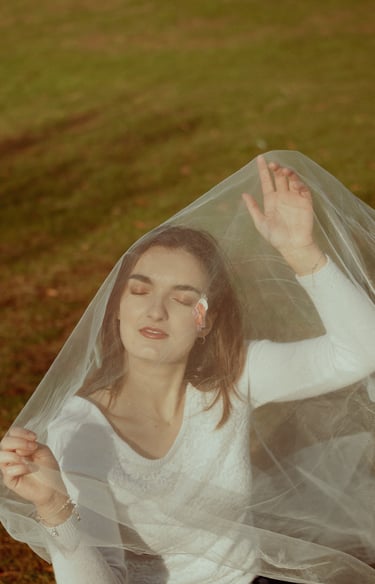 plan éloigné d'un visage féminin fermant les yeux et recouvert d'un voile en tulle transparent