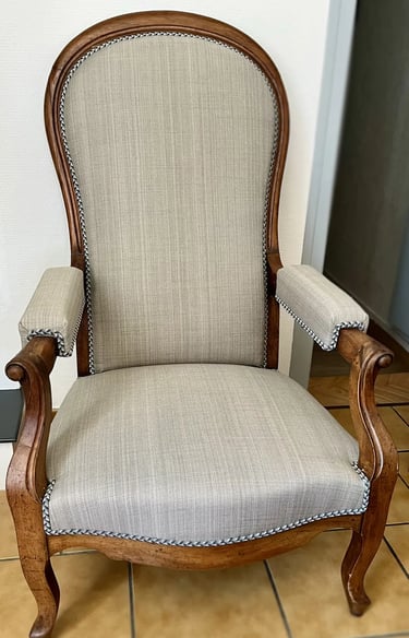 Chaise Voltaire avec assise en tissu gris et cadre en bois, dotée d'un dossier à bascule