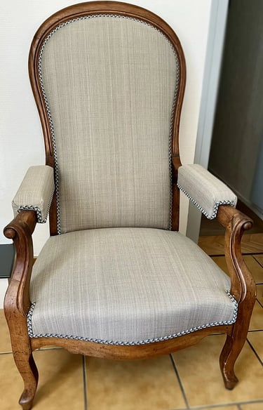 Chaise Voltaire avec assise en tissu gris et cadre en bois, dotée d'un dossier à bascule