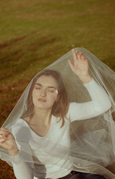 plan éloigné d'un visage féminin fermant les yeux et recouvert d'un voile en tulle transparent