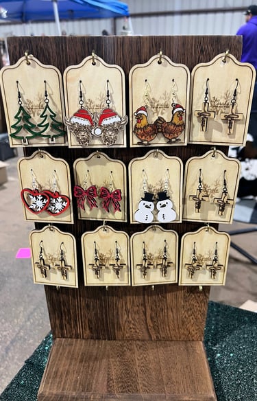 Wooden display fo handmade earrings with holiday and nature designs.