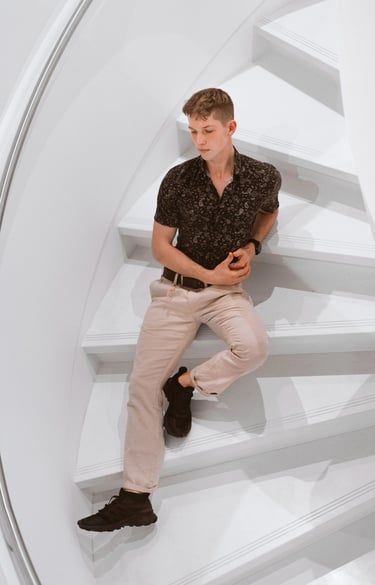 Portrait photo of a young man sitting on white stairs