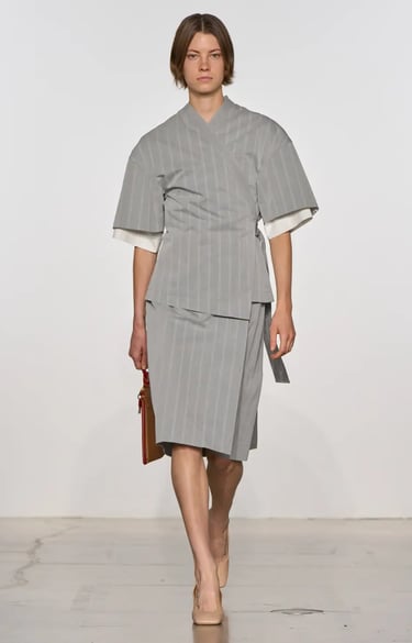 Calvin Klein Spring Summer 2026 runway model in pinstripe wrap skirt suit.