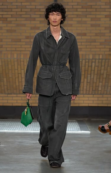 Calvin Klein Spring Summer 2026 runway look featuring grey utilitarian suit with green handbag.