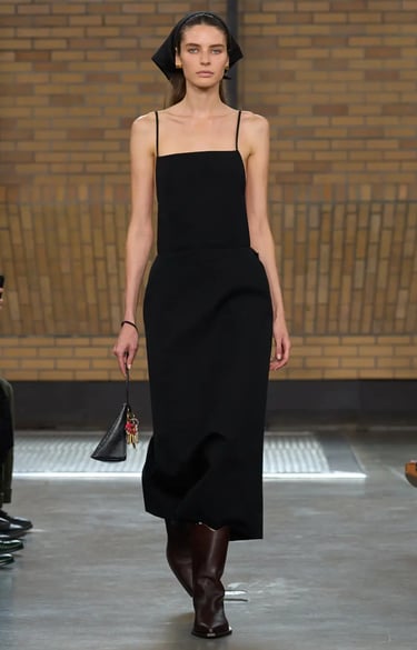 Calvin Klein Spring Summer 2026 runway model in sleek black slip dress with headscarf.