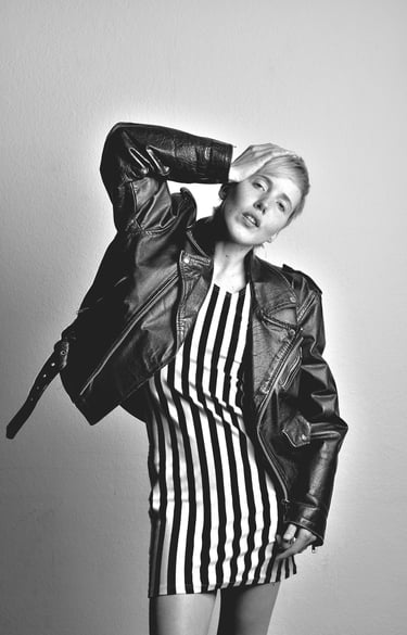a woman in a striped dress and leather jacket posing for a photo