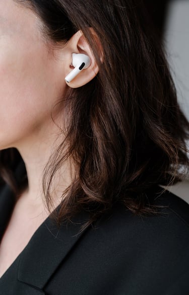 Profile of a women with long, dark hair, with air pods in her ears.