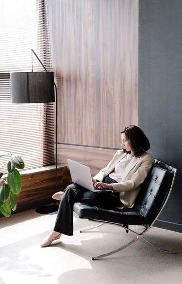 A woman sitting in a black chair typing on a laptop
