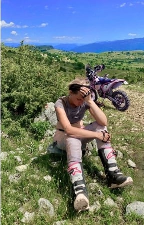 Yogalehrerin-Anja-sitzt-erschöpft-neben-dem-Enduromotorrad