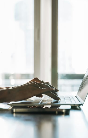 A woman with long blonde hair working on a laptop.