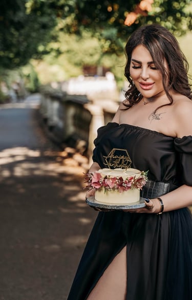 Outdoor portrait of woman in black dress holding cake – Fred Art Studio London