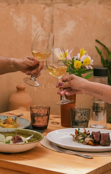 Dos copas brindan la comida que han pedido Es Mestral, se trata de solomillo, pescado fresco y unas alcachofas