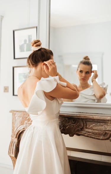 a woman in a white dress standing in front of a mirror
