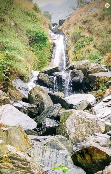 Bhagsunag Waterfall cascading through rocky boulders near McLeod Ganj, Himachal Pradesh.