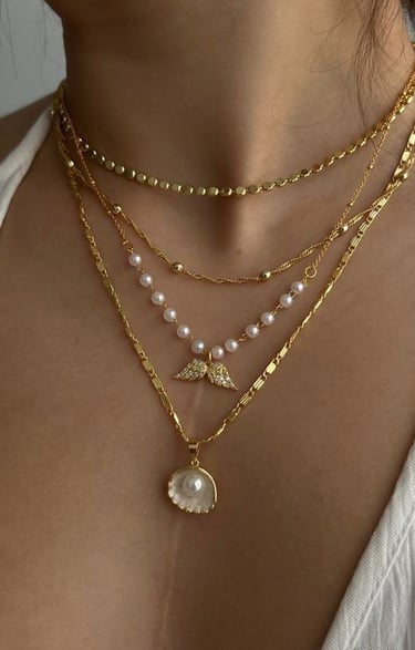 a woman wearing a white top and gold necklaces