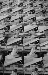 White‑costumed women at white pianos in a black‑background set, resembling a dreamlike rehearsal hal