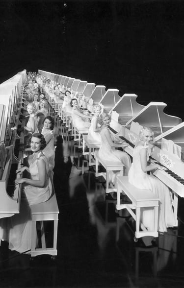 Regimented rows of white grand pianos played by chorus girls in white costumes, forming an endless l