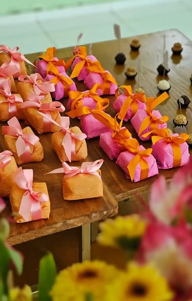 Mesa decorada com doces, incluindo bem-casados embalados em papel colorido e laços vibrantes,