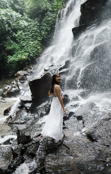 Portrait photoshoot of woman standing on rocks at Kanto Lampo Waterfall Bali