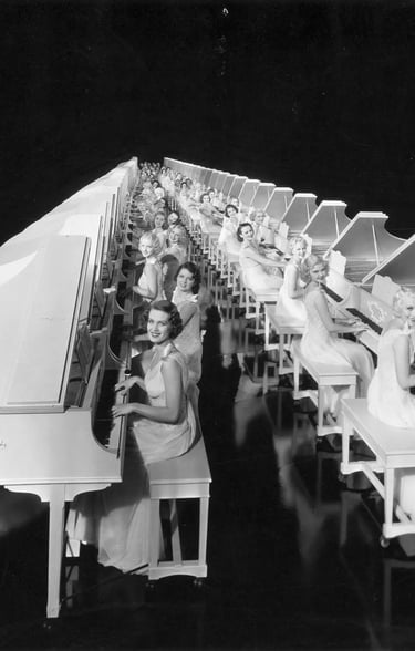 Regimented rows of white grand pianos played by chorus girls in white costumes, forming an endless l