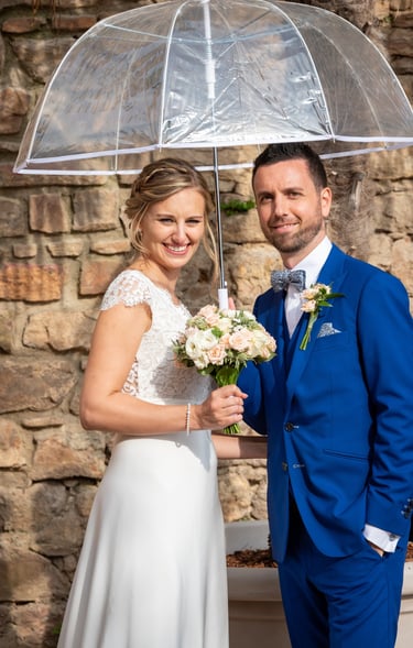 a bride and groom standing under a clear umbrella