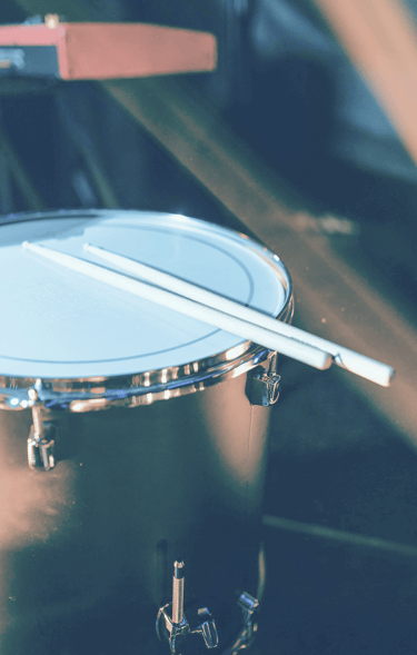 redish blue tint to upclose image of drums and drumsticks