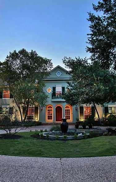 a large house with a fountain in the middle of the yard