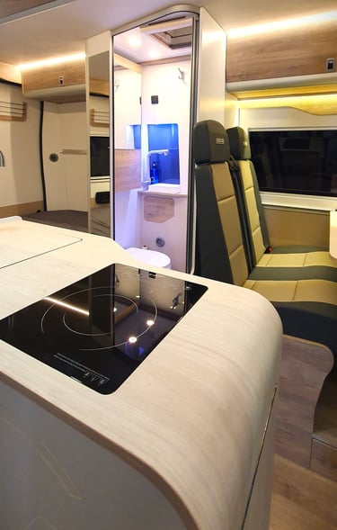 Zona de cocina, baño y asientos traseros de una furgoneta camperizada por Innovans