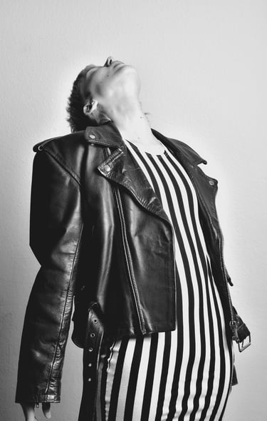 a woman in a striped dress and leather jacket posing for a photo
