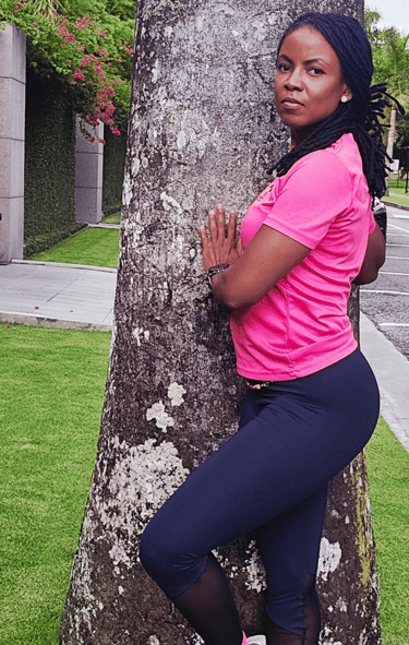 a woman in a pink shirt is leaning against a tree
