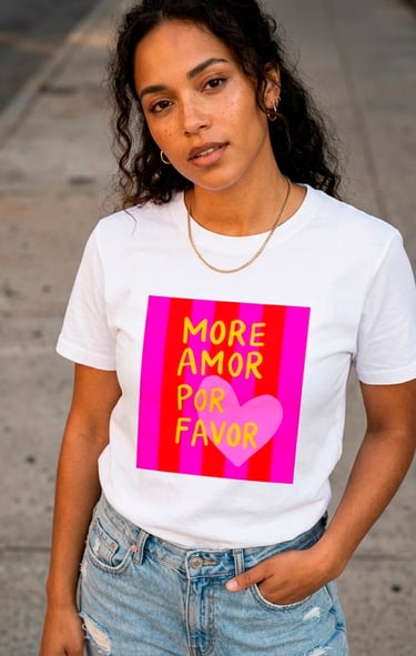 Woman wearing a white More Amor Por Favor graphic t-shirt with a pink heart and red stripes.