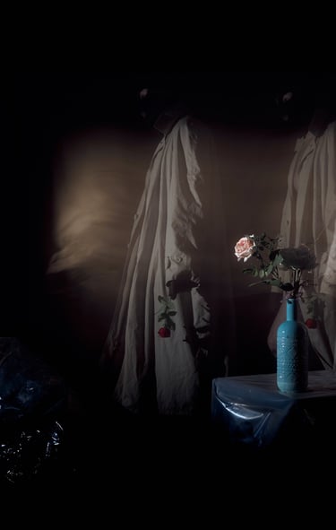 Surreal art piece featuring shadowy figures in trench coats near a blue vase with roses.