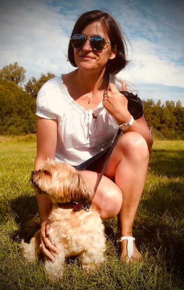 Femme accroupie dans l’herbe avec son chien, moment de complicité en extérieur.