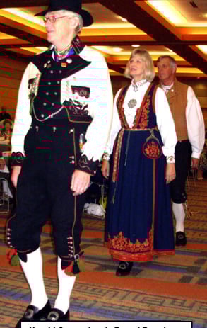Aman in a bunad followed by a woman and another man in a bunad parade