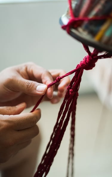 Manos tejiendo cordón de macramé para joyería artesanal hecha a mano con técnica tradicional.
