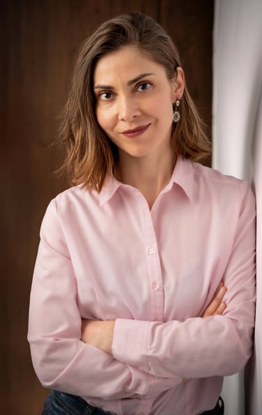 a corporate woman in a pink shirt and jeans leaning against a wall