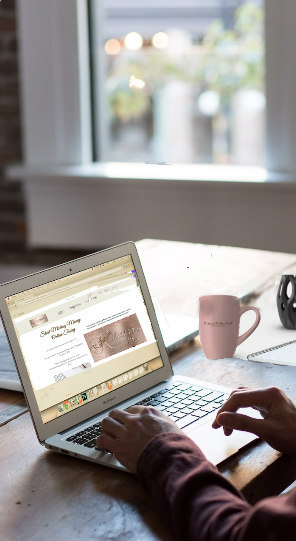 a person sitting at a desk with a laptop and a cup of coffee