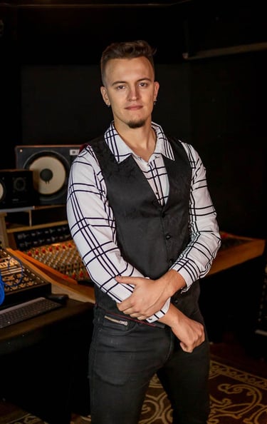 Guitarist and singer Lucas Vianna wearing a white shirt with black stripes and a black vest.