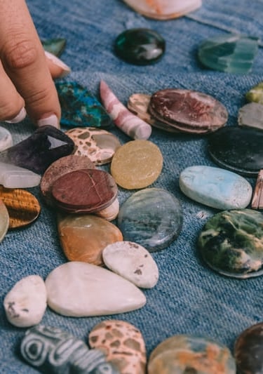 Selección de piedras y minerales naturales para joyería artesanal hecha a mano sobre tela azul.