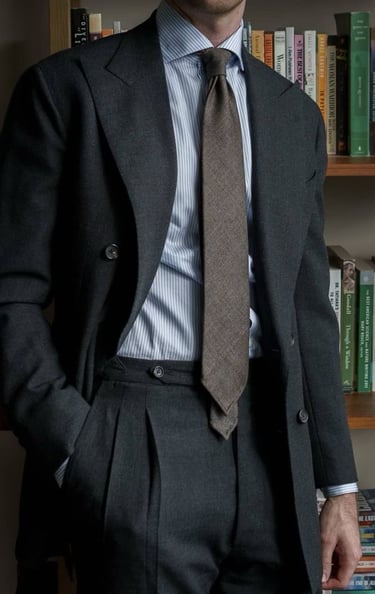 a man in a suit and tie is standing in front of a bookcase