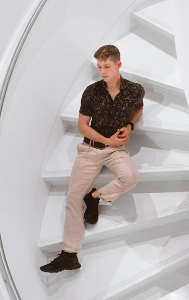 Portrait photo of a young man sitting on white stairs