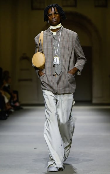 Model in oversized checked blazer and wide-leg trousers at Coach Spring/Summer 2026 runway show.